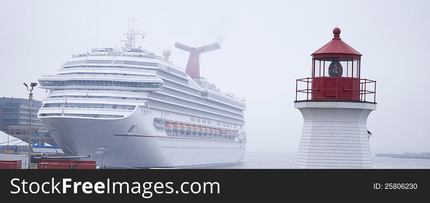 Luxury white cruise ship shot with light house on a clear day with calm seas and blue sky