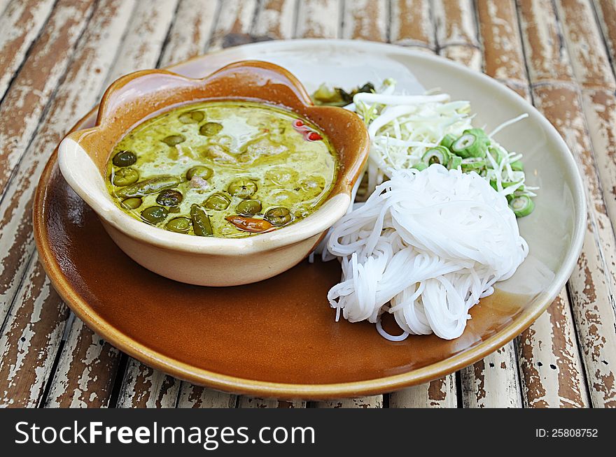 Rice noodle with ckicken green curry (Thai food) on bamboo table