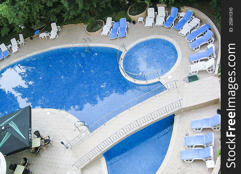 Swimming pool in the hotel with relax chairs and vegetation
