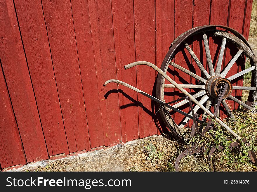 Old Wagon wheel and plow against a red wall. Old Wagon wheel and plow against a red wall