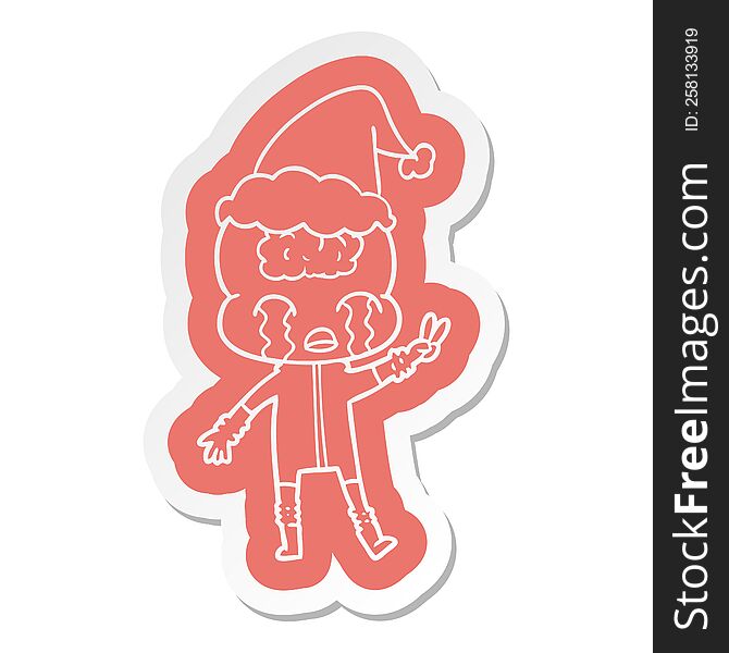 quirky cartoon  sticker of a big brain alien crying and giving peace sign wearing santa hat