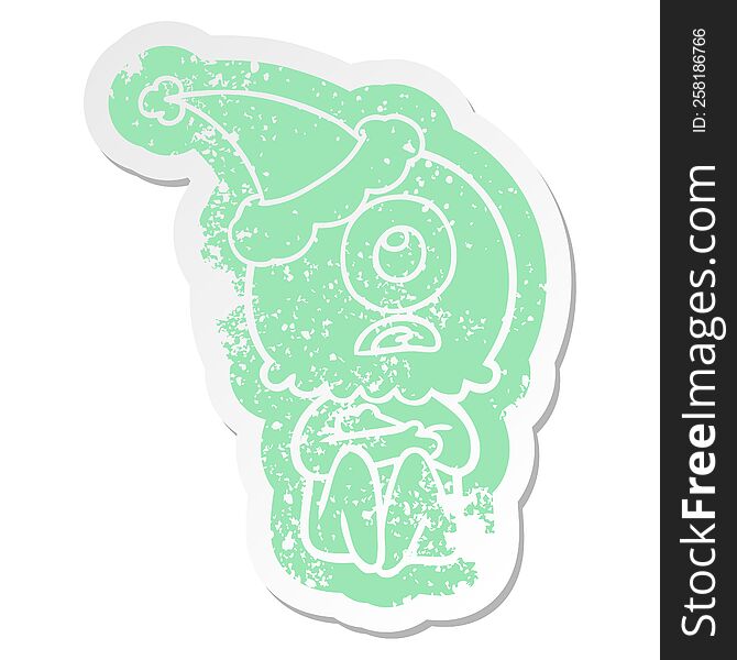 Cartoon Distressed Sticker Of A Cyclops Alien Spaceman Wearing Santa Hat
