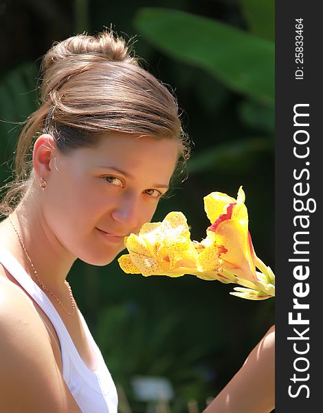 Portrait of a girl with a flower on the outside of the background flora. Portrait of a girl with a flower on the outside of the background flora