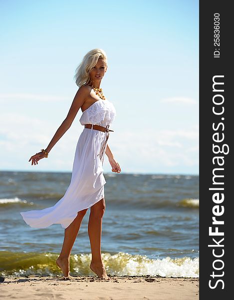 Blonde in a white dress on the beach