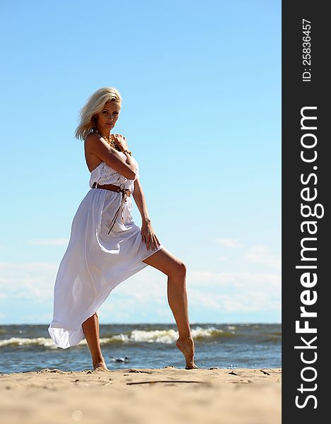 Blonde in a white dress on the beach