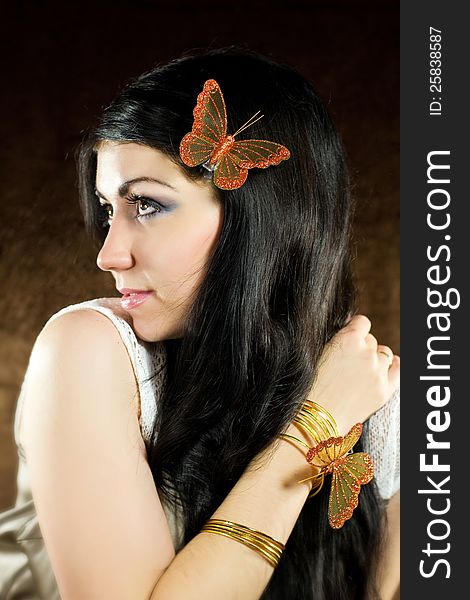 Brunette with brown-gold butterfly against the brown background