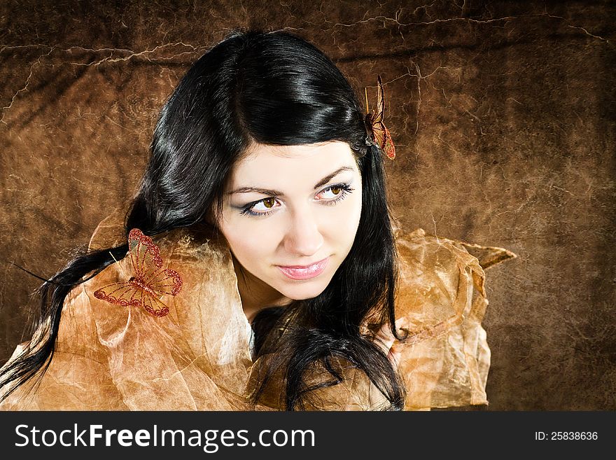 Brunette with brown-gold butterfly against the brown background