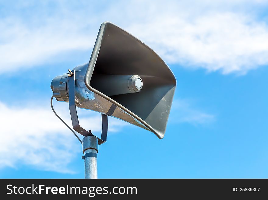 A loudspeaker with a cloudy blue sky background