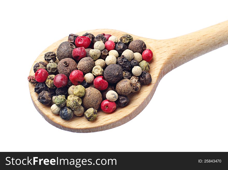 Colored peppers on a wooden spoon isolated on white