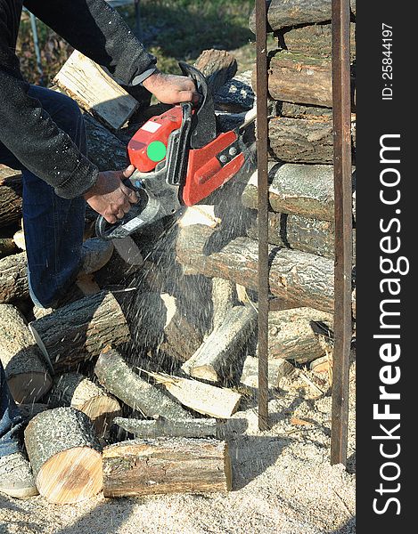 Man cuts a log for a wood stove. Man cuts a log for a wood stove