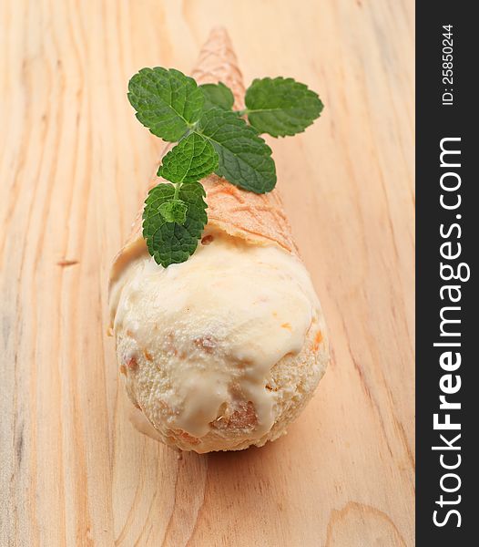 Cone of apricot icecream on wooden background. Cone of apricot icecream on wooden background