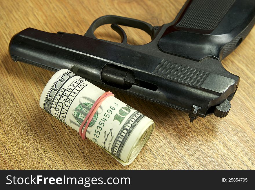 Dollars and a gun on the wooden table