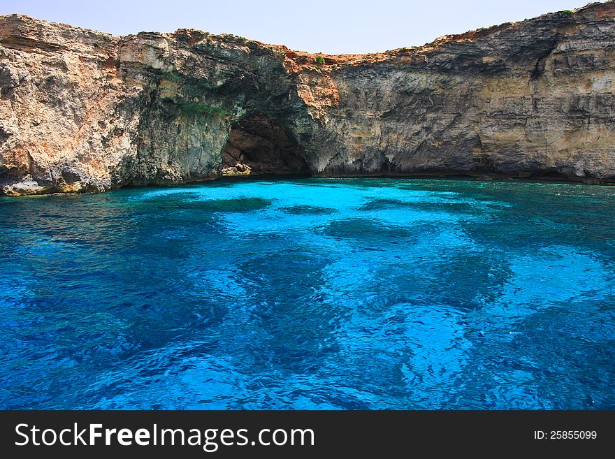 Vibrant turquoise lagoon and cliffs in Mediterranean Sea with sea cave in back. Vibrant turquoise lagoon and cliffs in Mediterranean Sea with sea cave in back