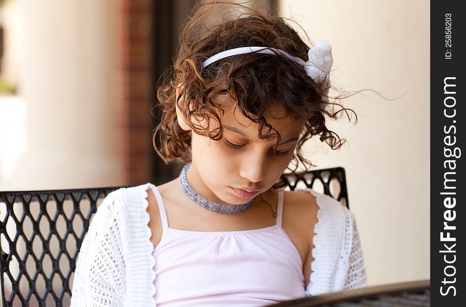 A sad or focused young girl sitting at a table. A sad or focused young girl sitting at a table.