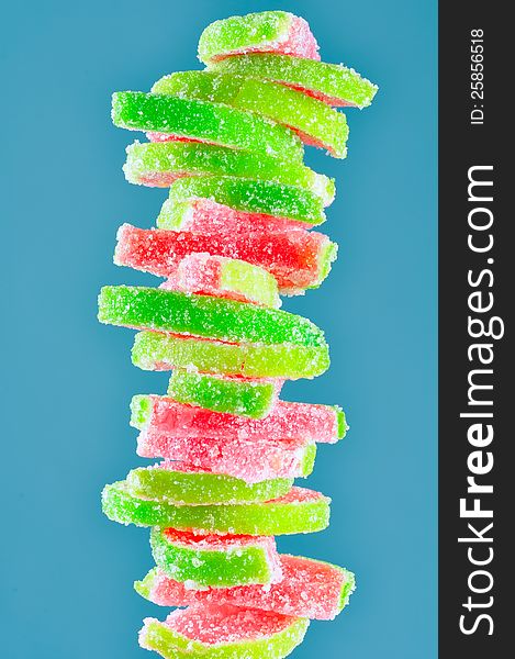 A stack of fruit jelly watermelon candies on a blue background - vertical orientation