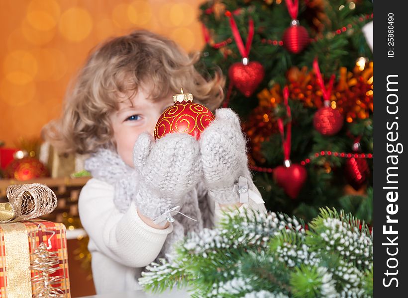 Happy child holding Christmas ball against decorated fir-tree. Happy child holding Christmas ball against decorated fir-tree