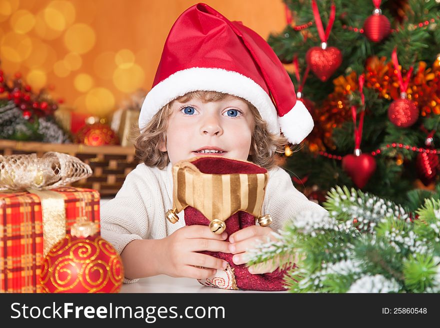 Happy child holding red sock against Christmas tree with decorations. Happy child holding red sock against Christmas tree with decorations