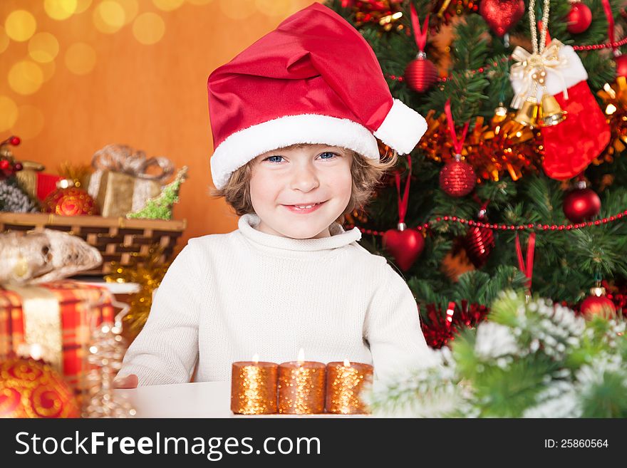 Happy child in Santa`s hat against Christmas tree with decorations. Happy child in Santa`s hat against Christmas tree with decorations