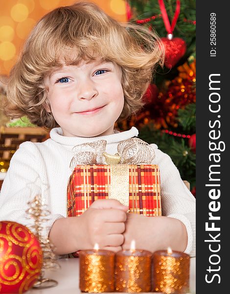 Happy child holding gift box against Christmas tree with decorations