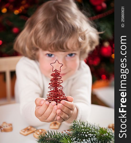 Happy child holding handmade decoration against Christmas lights. Happy child holding handmade decoration against Christmas lights