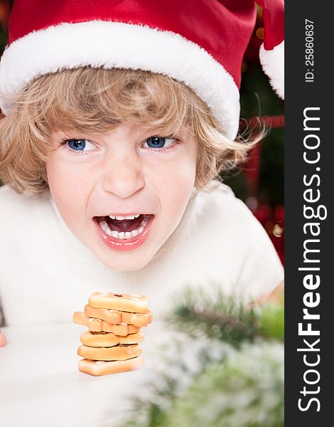 Funny smiling child in Santa`s hat eating Christmas cookies. Funny smiling child in Santa`s hat eating Christmas cookies