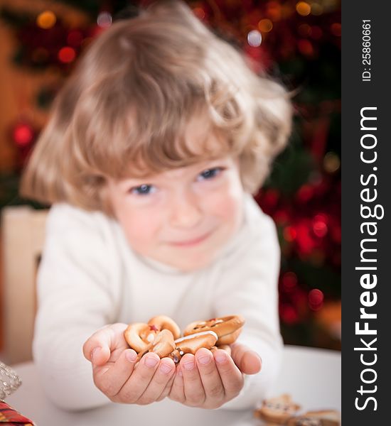 Happy child holding cookies against Christmas lights background