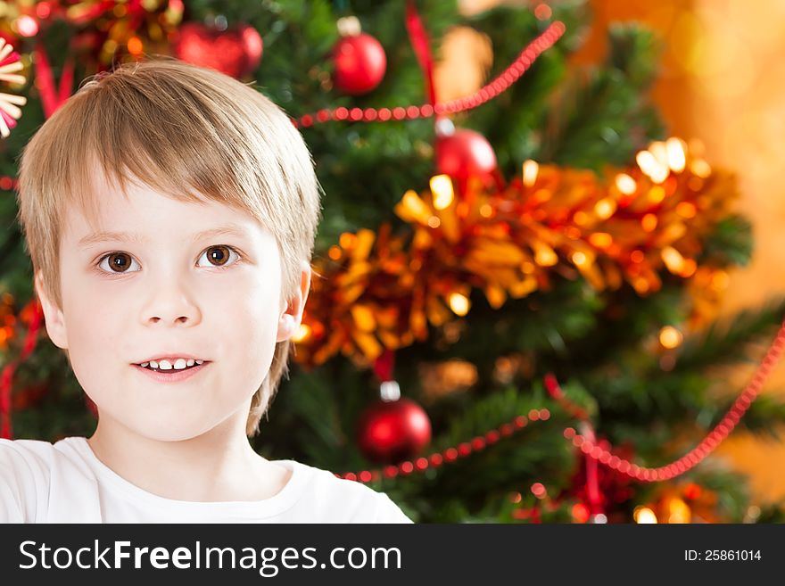 Closeup portrait of happy boy looking up against decorated Christmas tree. Closeup portrait of happy boy looking up against decorated Christmas tree