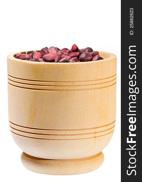 Wooden cup with cedar nuts on white background