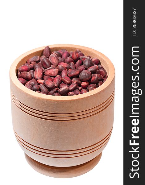 Wooden cup with cedar nuts on white background