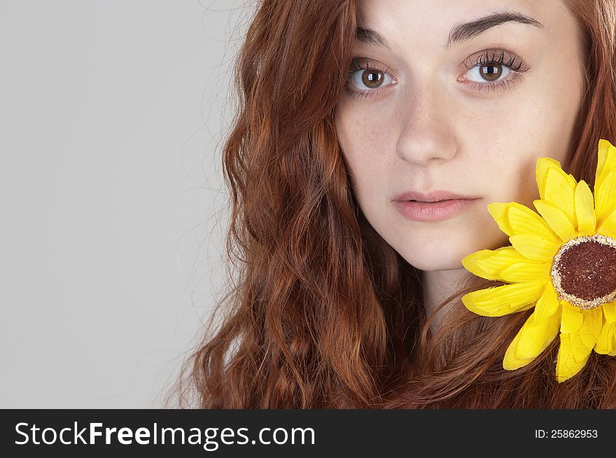 Portrait of a red haired girl of nineteen with yellow flower on her shoulder. Portrait of a red haired girl of nineteen with yellow flower on her shoulder