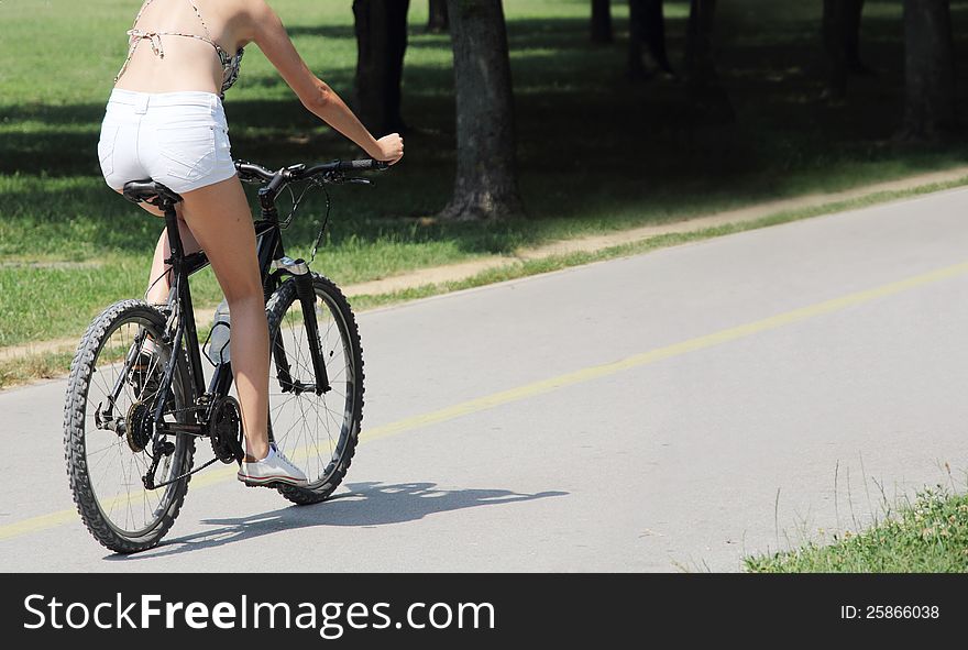 A young woman riding a bicycle on the bike trail in the park. A young woman riding a bicycle on the bike trail in the park