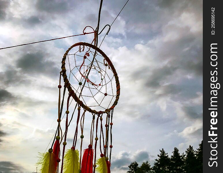 Dream Catcher. Photo of a dream catcher against the background of the sky and the forest.