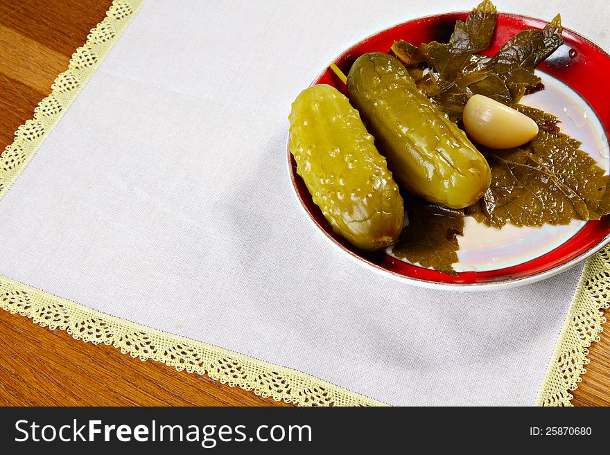 Marinated cucumbers on plate with garlic and currant leaf