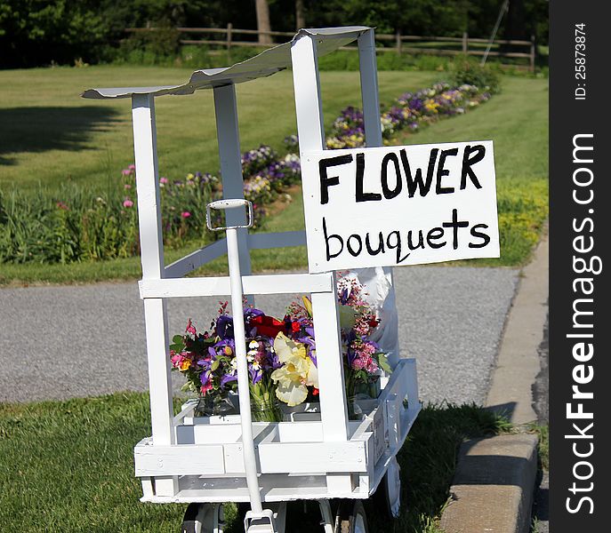 A handmade flower stand and sign at the end of a driveway,with bunches of fresh picked flowers for sale. A handmade flower stand and sign at the end of a driveway,with bunches of fresh picked flowers for sale.