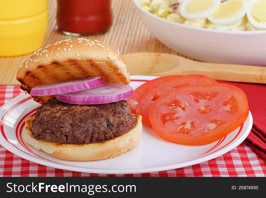 Hamburger with tomato and onion on a grilled bun. Hamburger with tomato and onion on a grilled bun