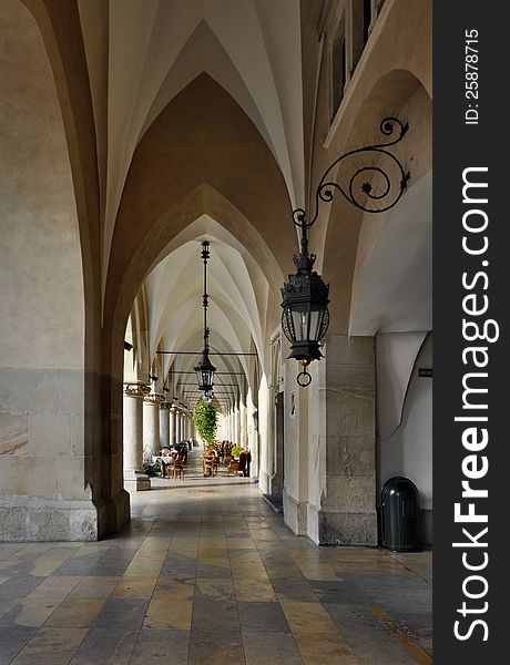 The gothic arcades of Sukiennice (Cloth Hall, Drapers' Hall) on the Main Market Square in Krakow, Poland, with an outdoor cafe. The gothic arcades of Sukiennice (Cloth Hall, Drapers' Hall) on the Main Market Square in Krakow, Poland, with an outdoor cafe