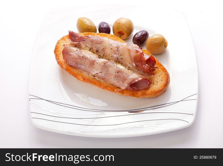 Salami open sandwich with olive on white dish