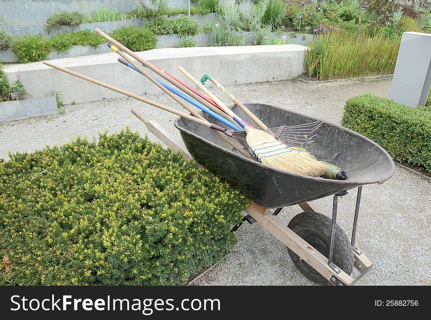 Wheelbarrow with garden tools in formal garden