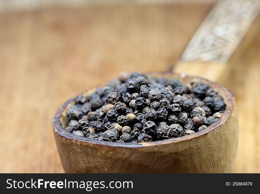 Black pepper in a wooden spoon