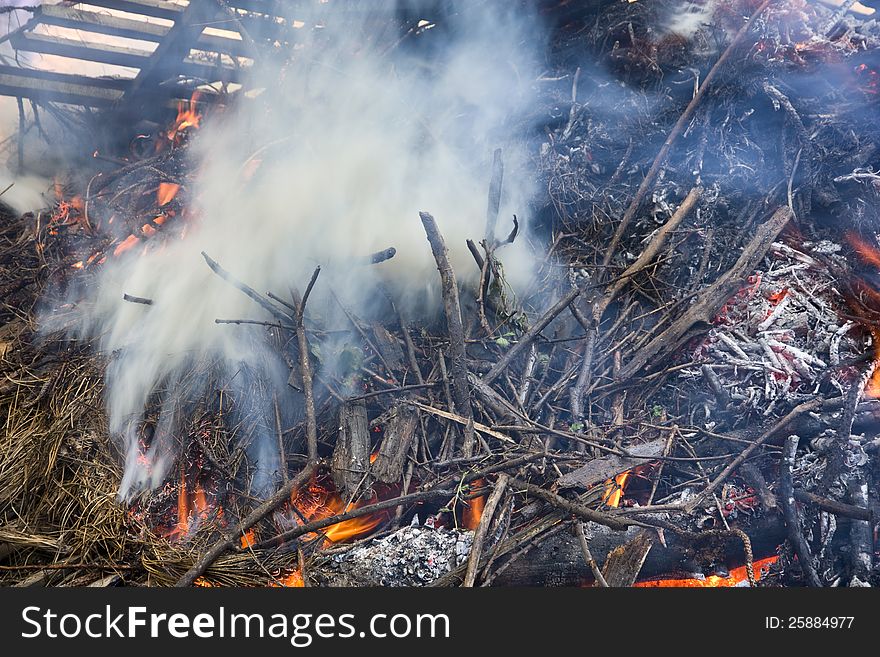 Detail the burning piles with branches and debris from the forest. Detail the burning piles with branches and debris from the forest