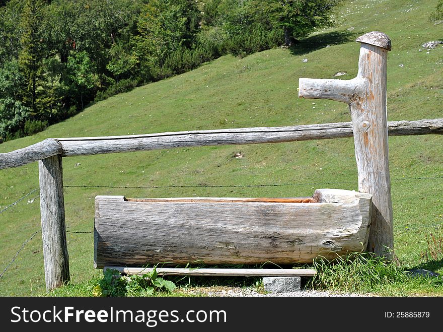 Wooden trough in the German Alps area, surrounded by green grass and trees. Wooden trough in the German Alps area, surrounded by green grass and trees