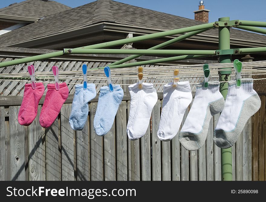 Pink,blue,white and grey socks on a clothesline hanging to dry outside. Pink,blue,white and grey socks on a clothesline hanging to dry outside