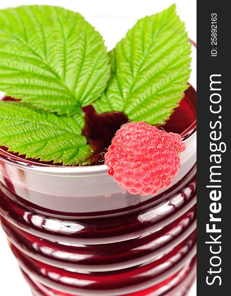 A glass of fresh berry juice with a red raspberry and green leaf close-up - high angle view. A glass of fresh berry juice with a red raspberry and green leaf close-up - high angle view