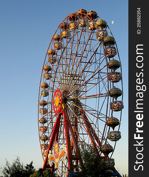Colourful big ferris wheel on the blue sky in park of rest and entertainments. Colourful big ferris wheel on the blue sky in park of rest and entertainments