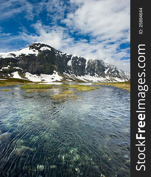 Norwegian landscape with a mountain on background and mountain river.