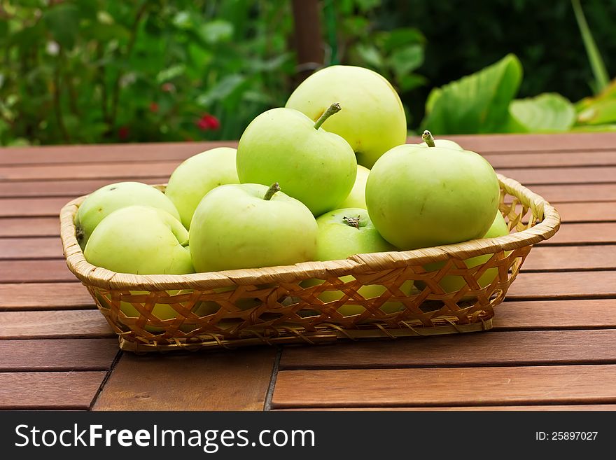 Fresh green apples in bucket on wooden surface