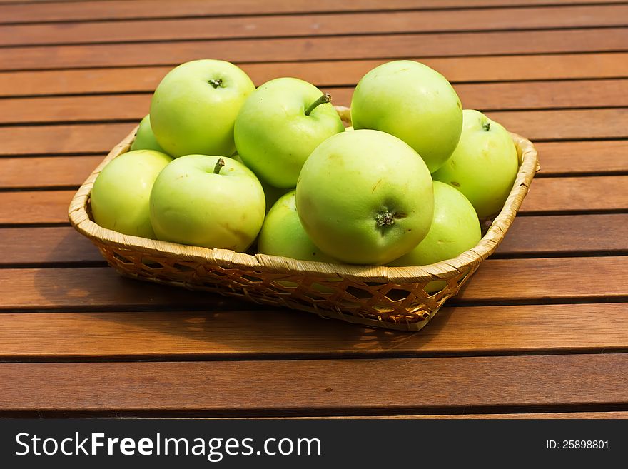 Set of fresh green apples in bucket on wooden background