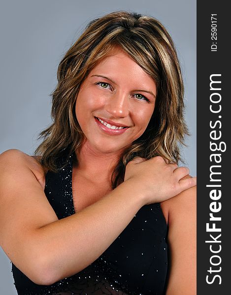 Glamour girl with black gown smiling over a neutral background.