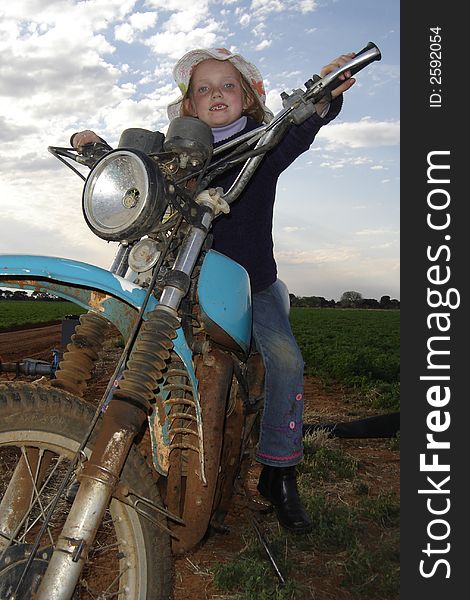 Young girl on old farm motorcycle. Young girl on old farm motorcycle.