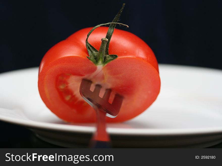 Tomato with stem on the plate and black background